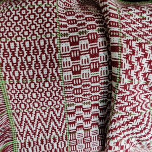 Woven fabric with various patterns, in red and white, with a some green.