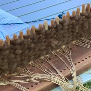 A peg loom with some weaving on it.